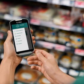 a person is holding a cell phone in their hand in a grocery store .