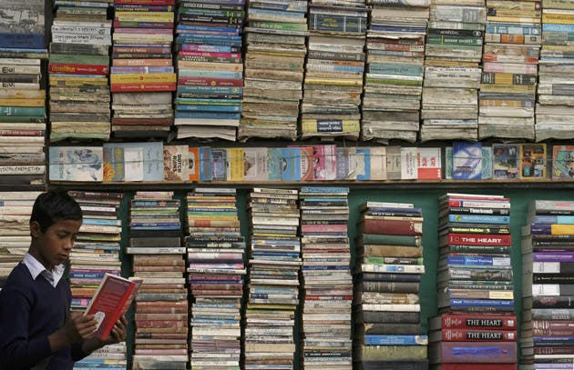 <p>FILE-A school boy reads a book from a roadside secondhand book shop in the northeastern Indian city of Siliguri</p>