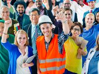 A group of diverse individuals, who represent various occupations, stand with their arms raised in the air. labor day; laborers; construction worker; teacher; nurse; doctor; assistant; office staff; blue collar; workforce