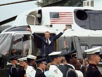 President Richard M. Nixon smiles and gives the victory sign as he boards the White House helicopter after his resignation on August 9, 1974 in Washington, D.C.