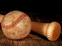 An old worn baseball and wood bat