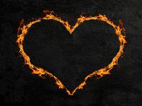 Fiery heart or heart made of flames with a dark concrete wall background. (love, Valentine's Day)