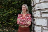 A portrait of a woman standing outside.