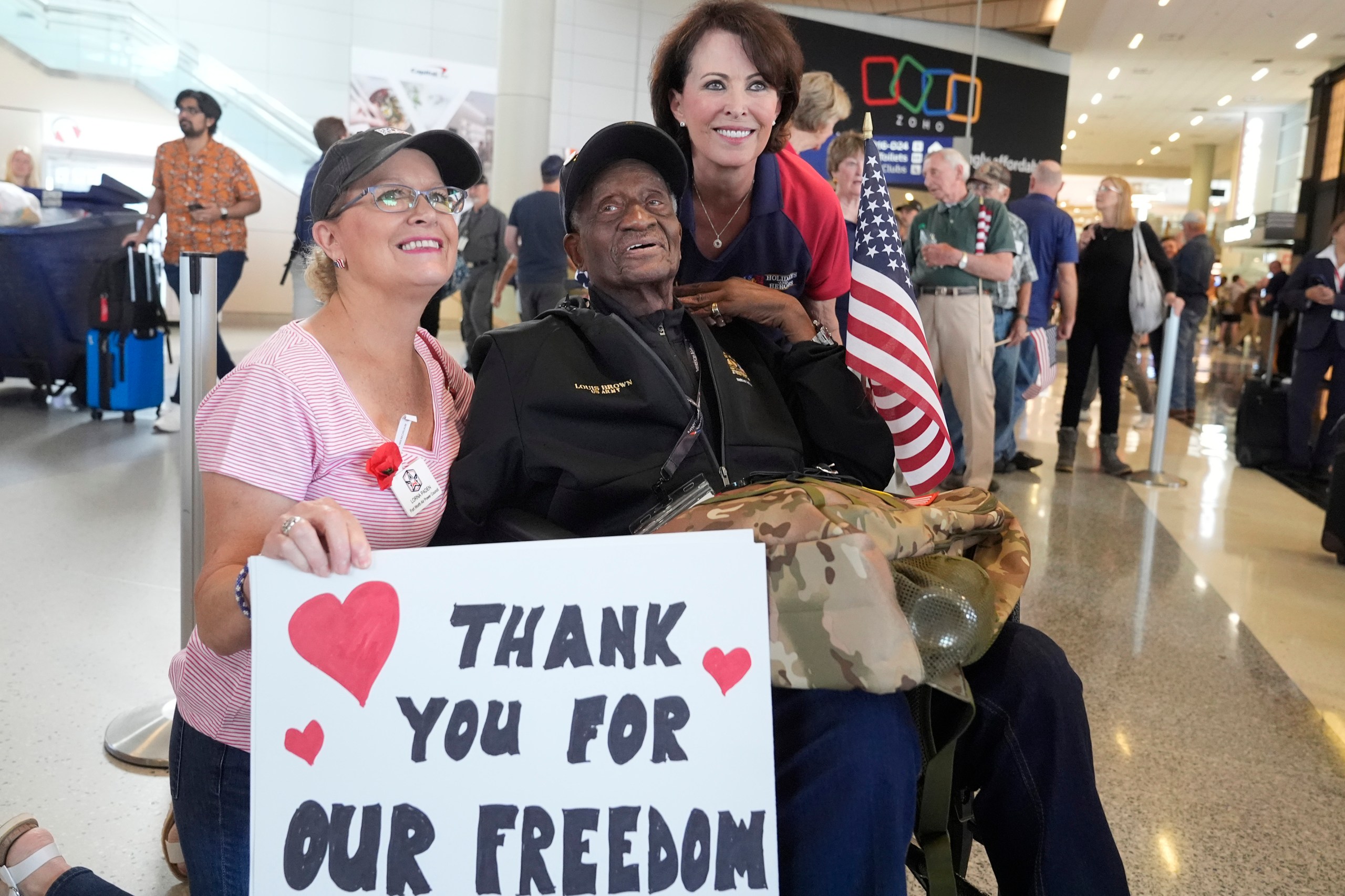 World War II veteran Louis Brown, center, poses for photos with Lorna Paden, left, and Kerre Randel before heading to board a flight with other veterans at Dallas Fort Worth International Airport in Dallas Friday, May 31, 2024. A group of World War II veterans are being flown from Texas to France where they will take part in ceremonies marking the 80th anniversary of D-Day. (AP Photo/LM Otero)