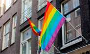 A pride flag flying on a pole attached to a building