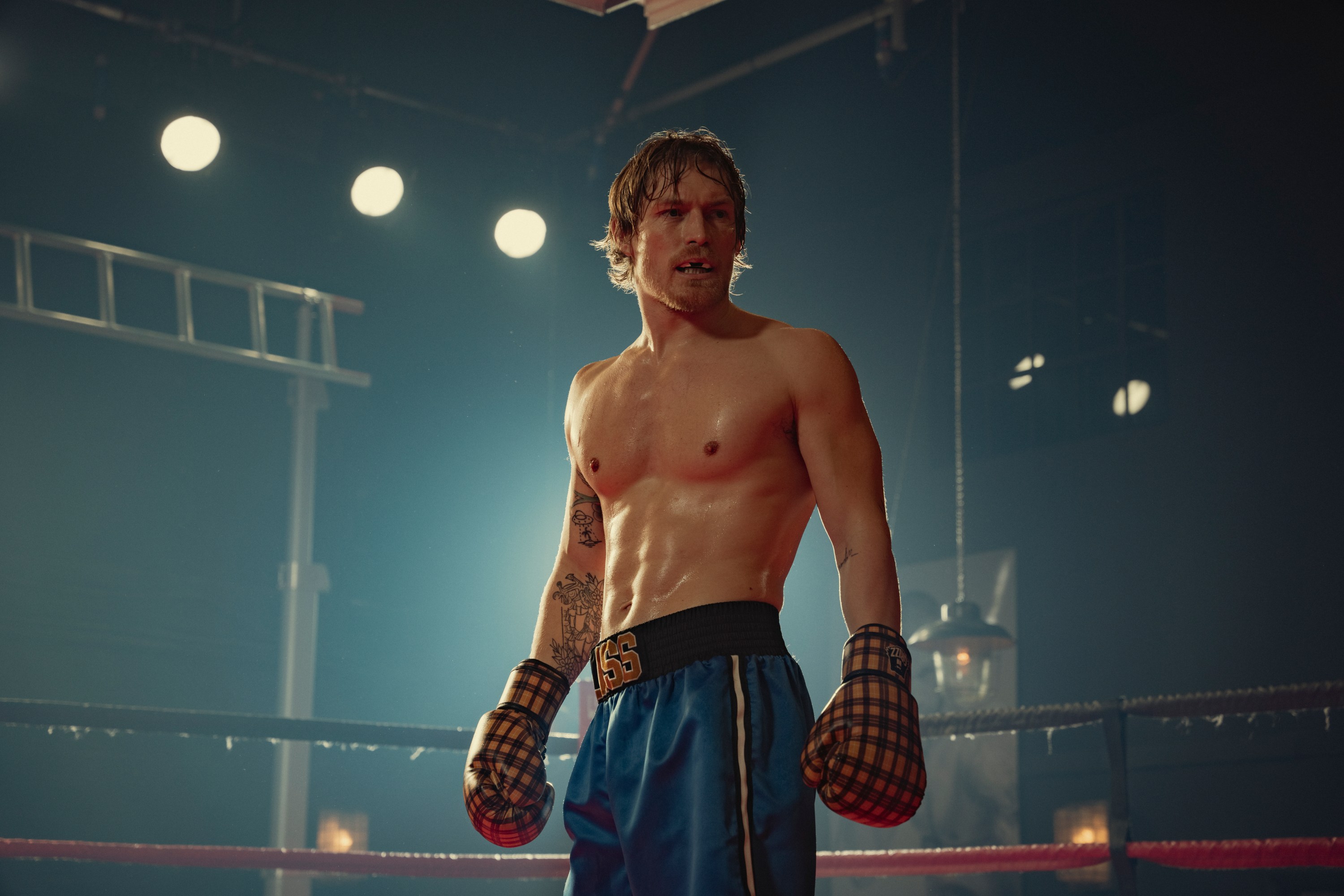 A sweaty and shirtless boxer stands in the ring alone in The Gentlemen on Netflix
