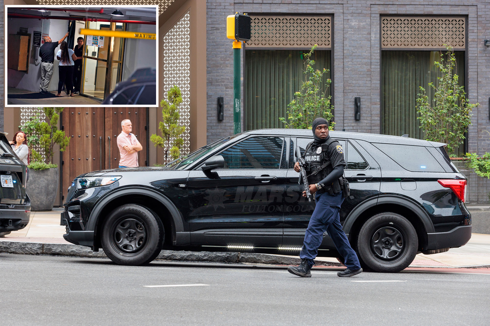 A police officer walks in the street carrying a large gun.