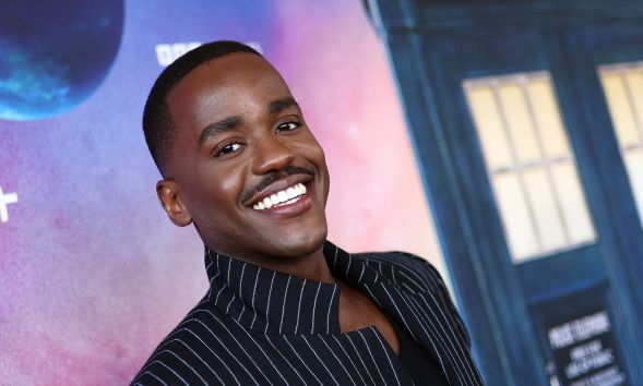 Ncuti Gatwa smiling in a black pinstriped suit at the Doctor Who premiere