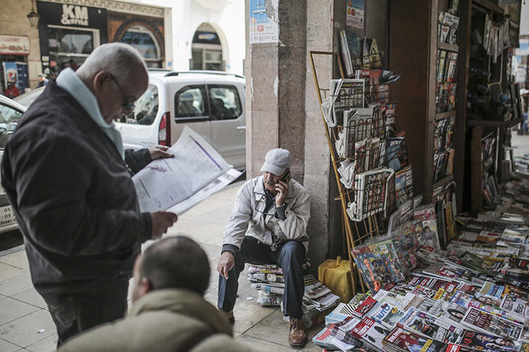 A man reads a newspaper at a stall near the Medina of Rabat, Morocco, on March 16, 2017. Morocco, Yemen, Oman, and Jordan recently ordered newspapers to cease production, citing fears of spreading the COVID-19 virus. (AP/Mosa'ab Elshamy)