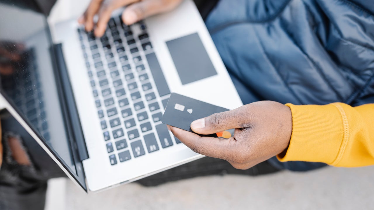 close up of hand holding credit card while working on laptop