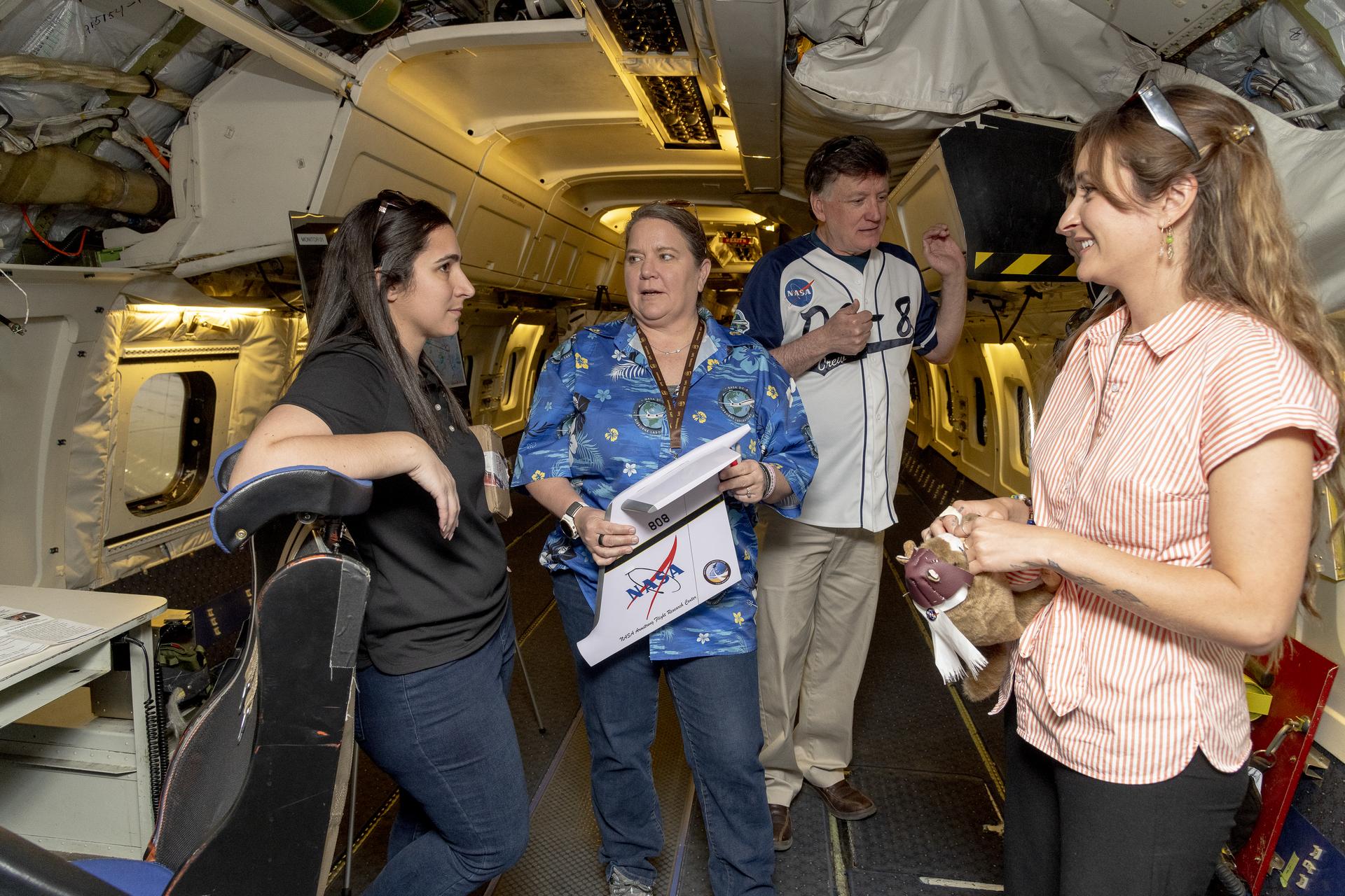 Four people converse onboard an aircraft.
