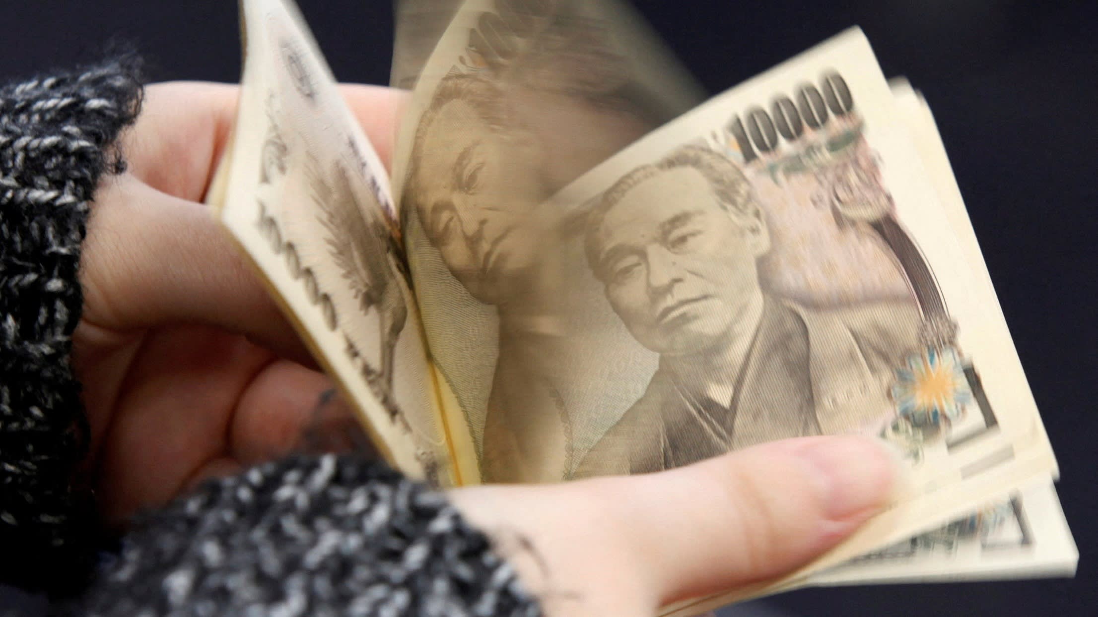 A woman counts Japanese 10,000 yen notes in Tokyo