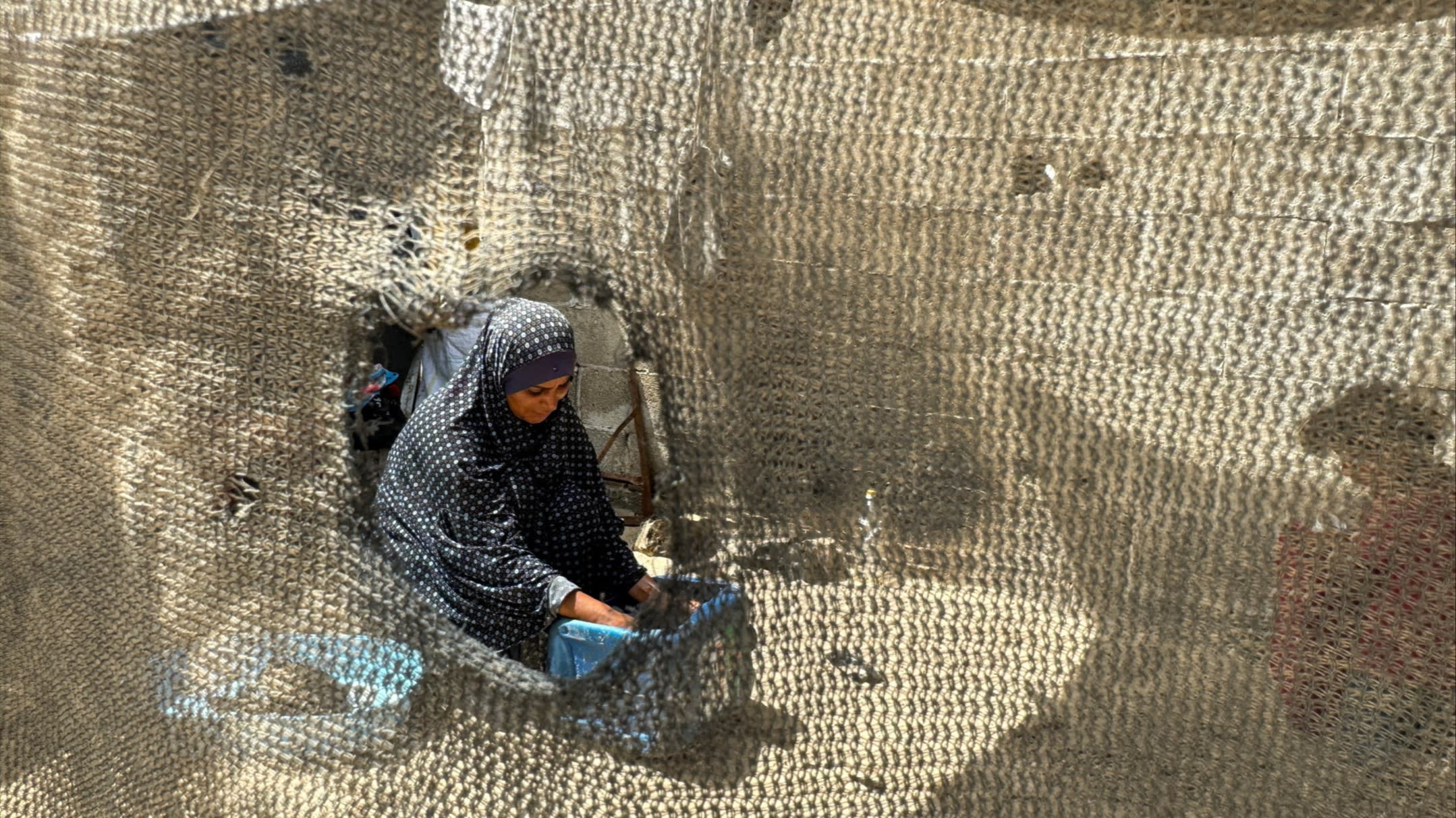 A displaced Palestinian woman washes clothes at a tent camp
