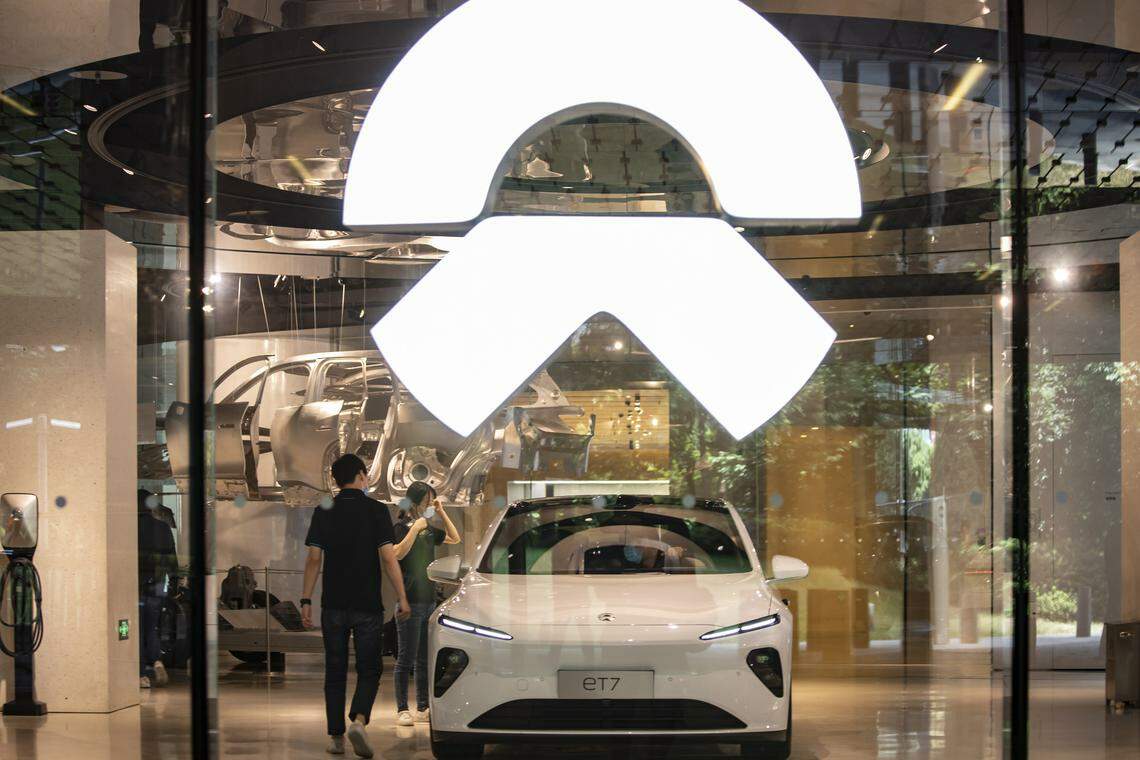 Employees stand next to a ET7 sedan at a NIO dealership in Shanghai, China, on Wednesday, June 08 2022. 