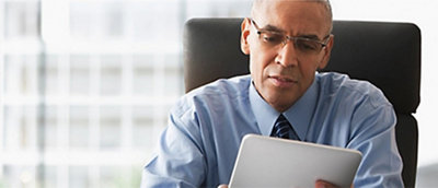 Um homem sentado em um escritório olhando para um tablet.
