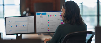 A woman sitting at a desk with two monitors.