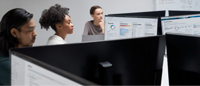 A group of people looking at monitors in an office.