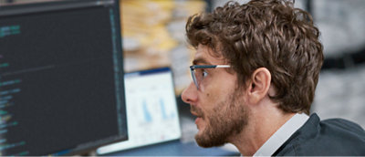 A man is wearing glasses and watching a desktop screen.