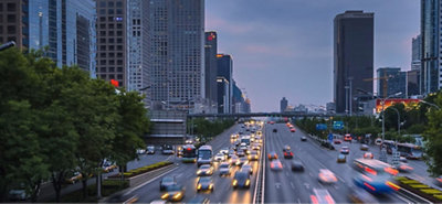 O tráfego flui em uma estrada de cidade de várias nuvens em um pôr-do-sol moderno, pendendo dos lados sob um céu de nuvem.