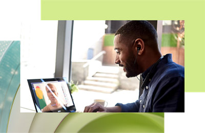 Um homem usando fones de ouvido trabalhando em um laptop em um ambiente de escritório moderno, em uma chamada de vídeo com uma mulher 