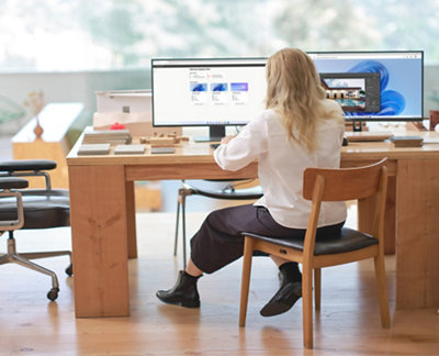 Ένα άτομο που κάθεται σε ένα γραφείο και κοιτάζει έναν υπολογιστή