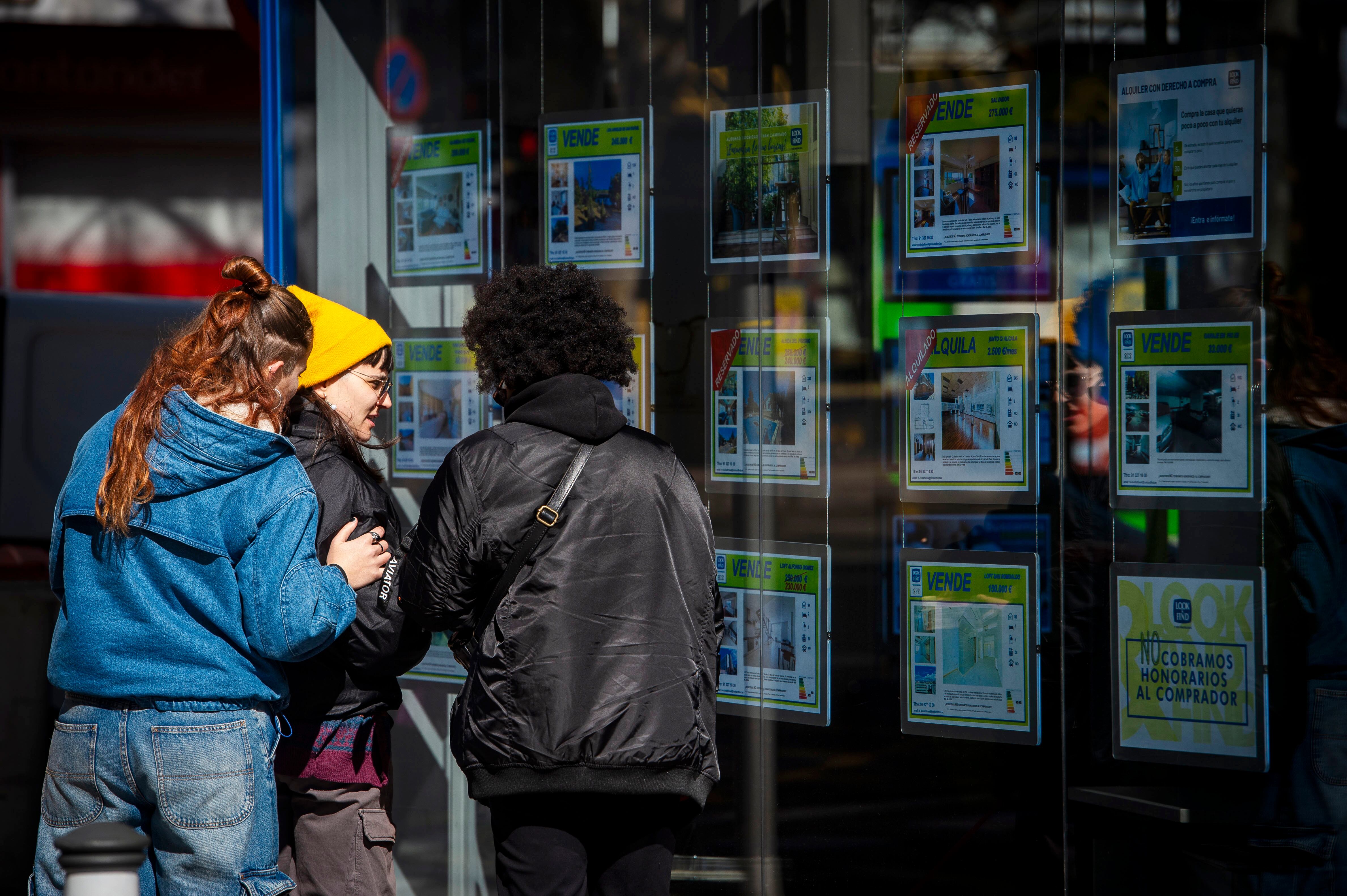 A group of young people look at the window of a real estate agency in Madrid, last February.