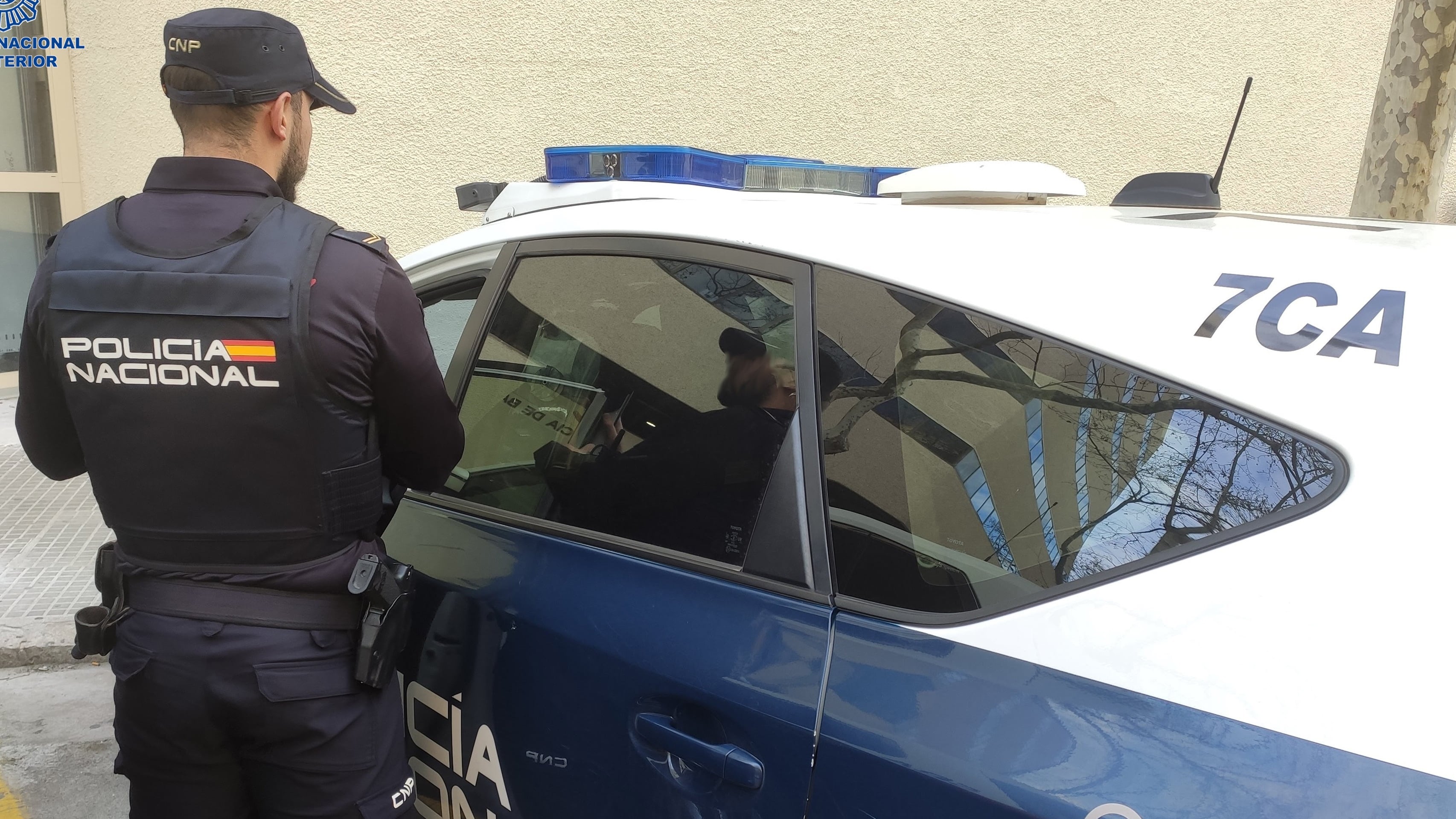 Un agente de la Policía Nacional, junto a un coche patrulla en agosto de 2023.