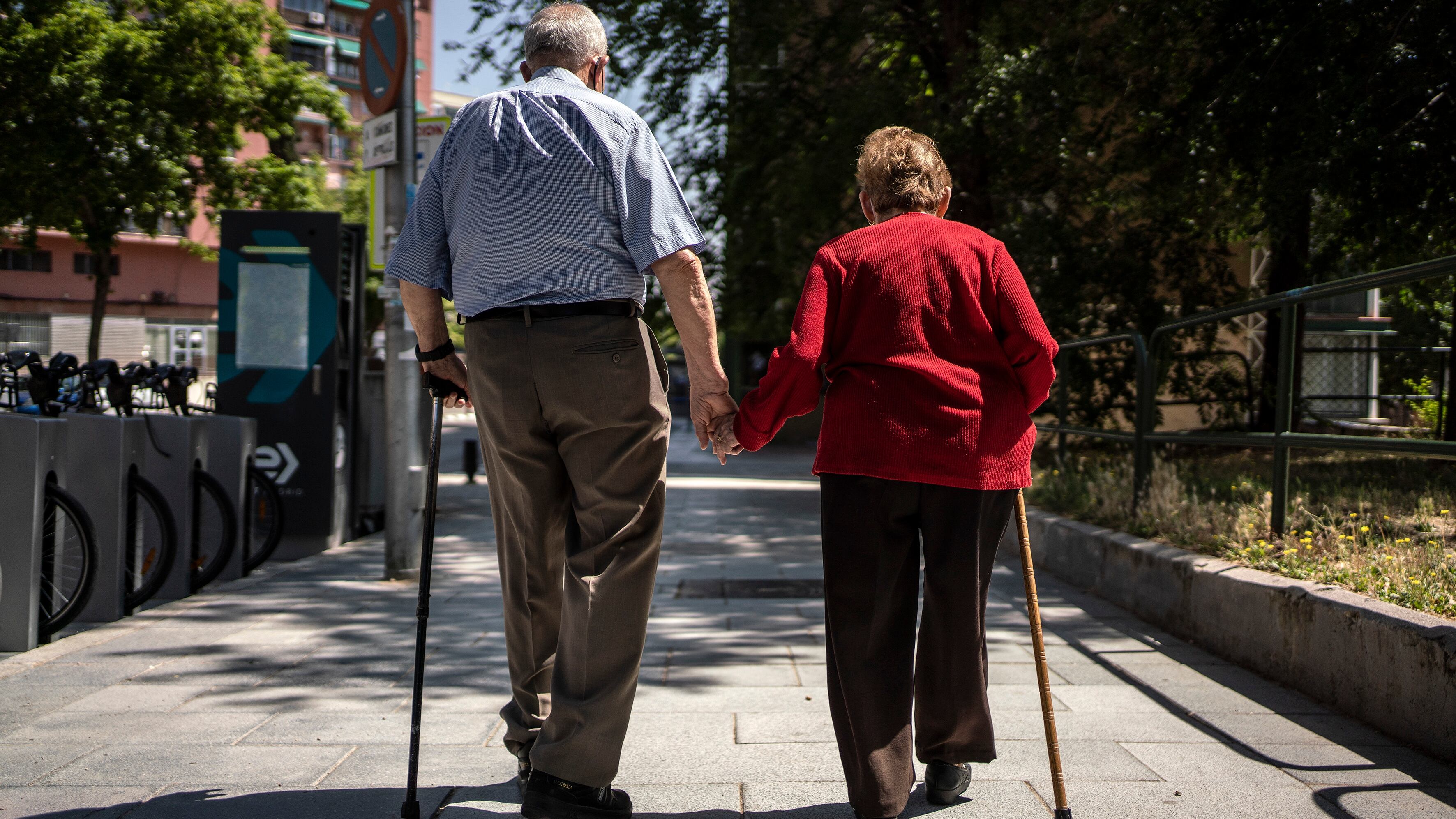 Two elderly people walk hand in hand in Madrid, Spain.