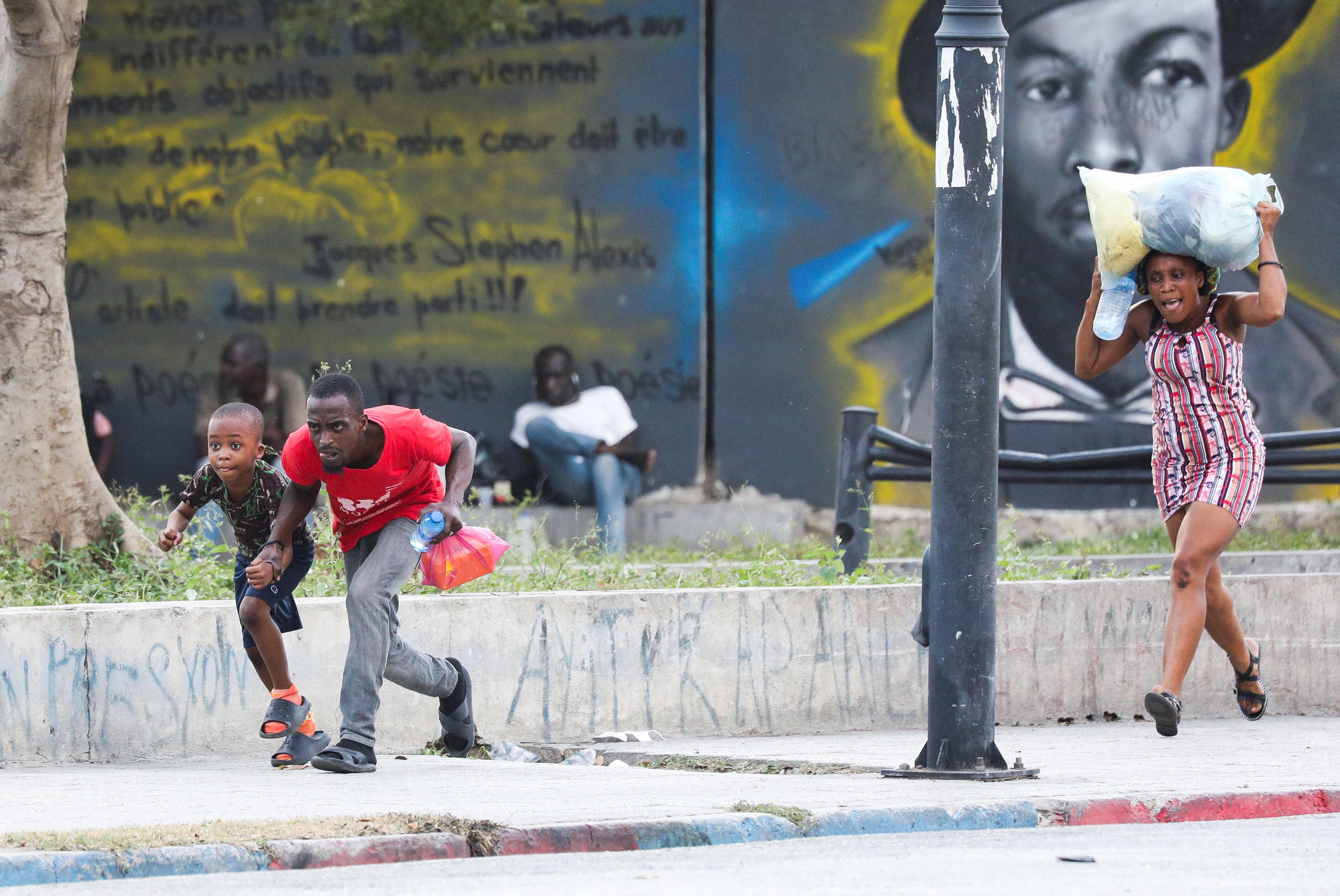 Several people run from a shooting near the National Palace in Port-au-Prince, on March 21.