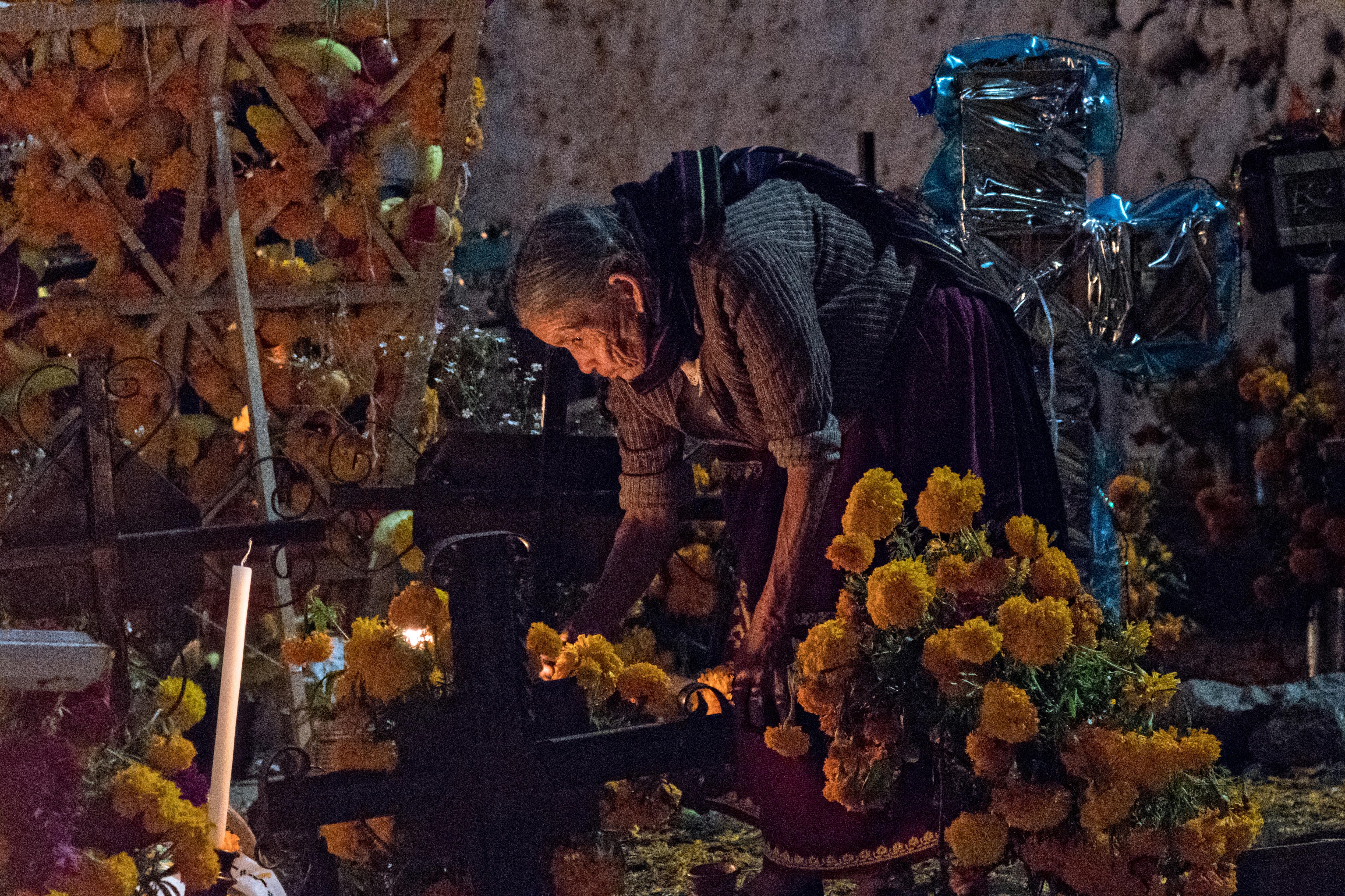 An Indigenous woman places a candle on the grave of a relative on Janitzio Island, Michoacán, Mexico.