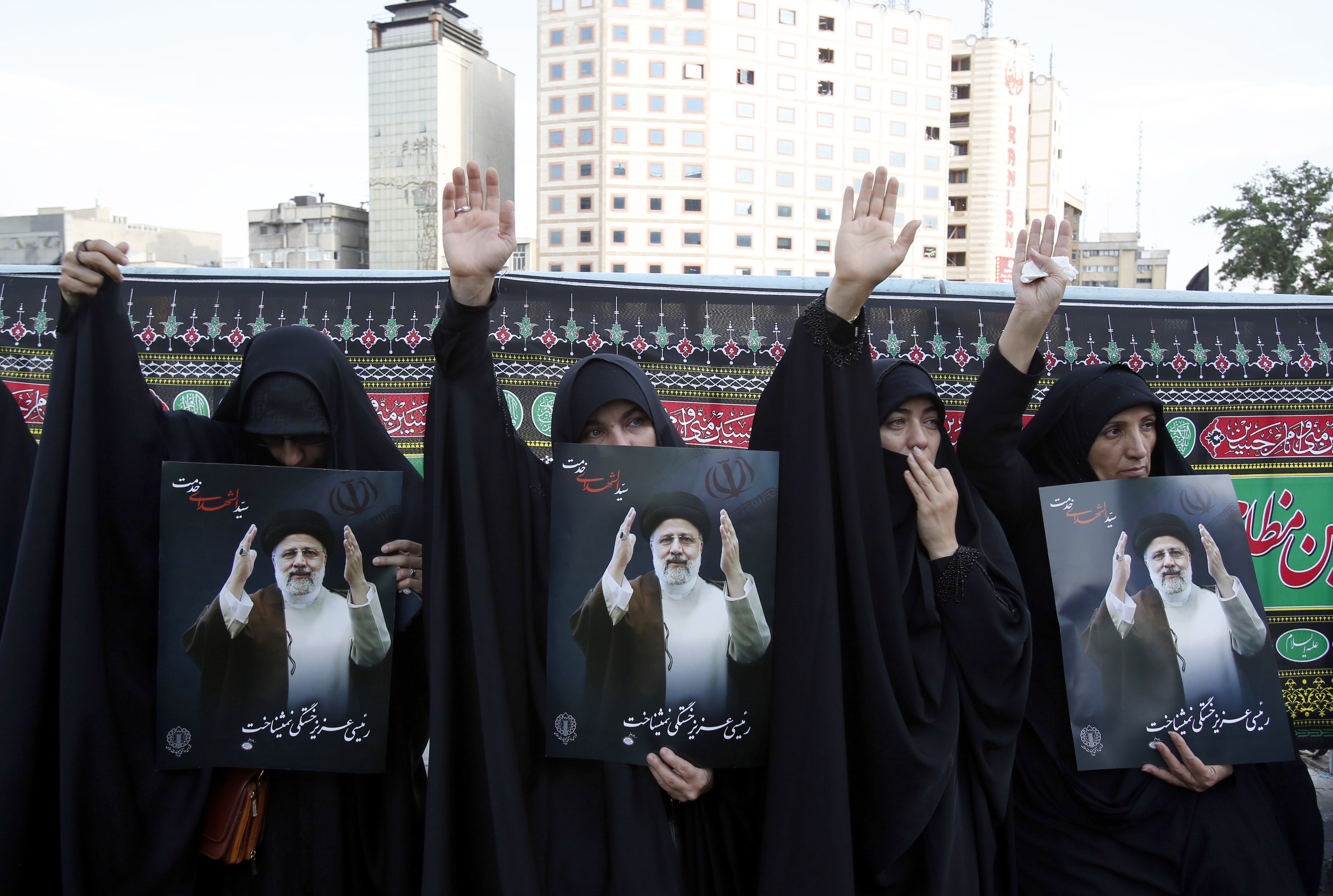 Iranian women hold portraits of the late president Ebrahim Raisi at a mourning ceremony in Tehran, on May 20, 2024.