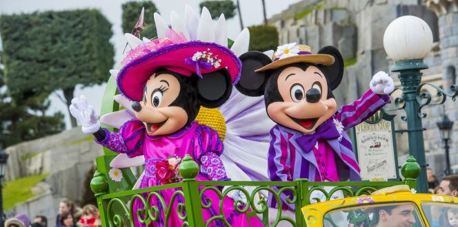 Minnie and Mickey Mouse during a parade at a Disney theme park.