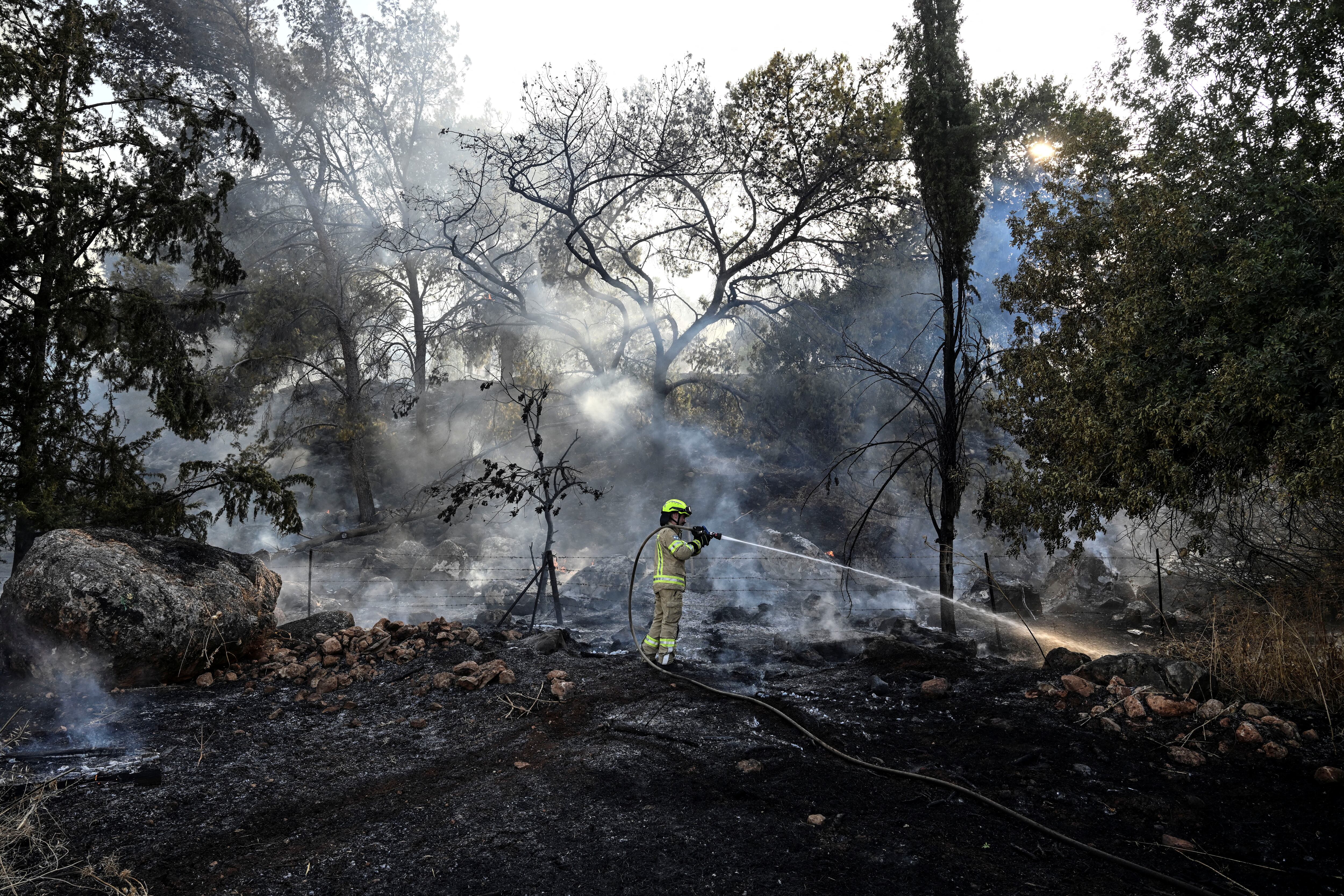 Un bombero israelí trata de apagar un incendio provocado por el ataque de Hezbolá, este jueves cerca de la frontera con Líbano.