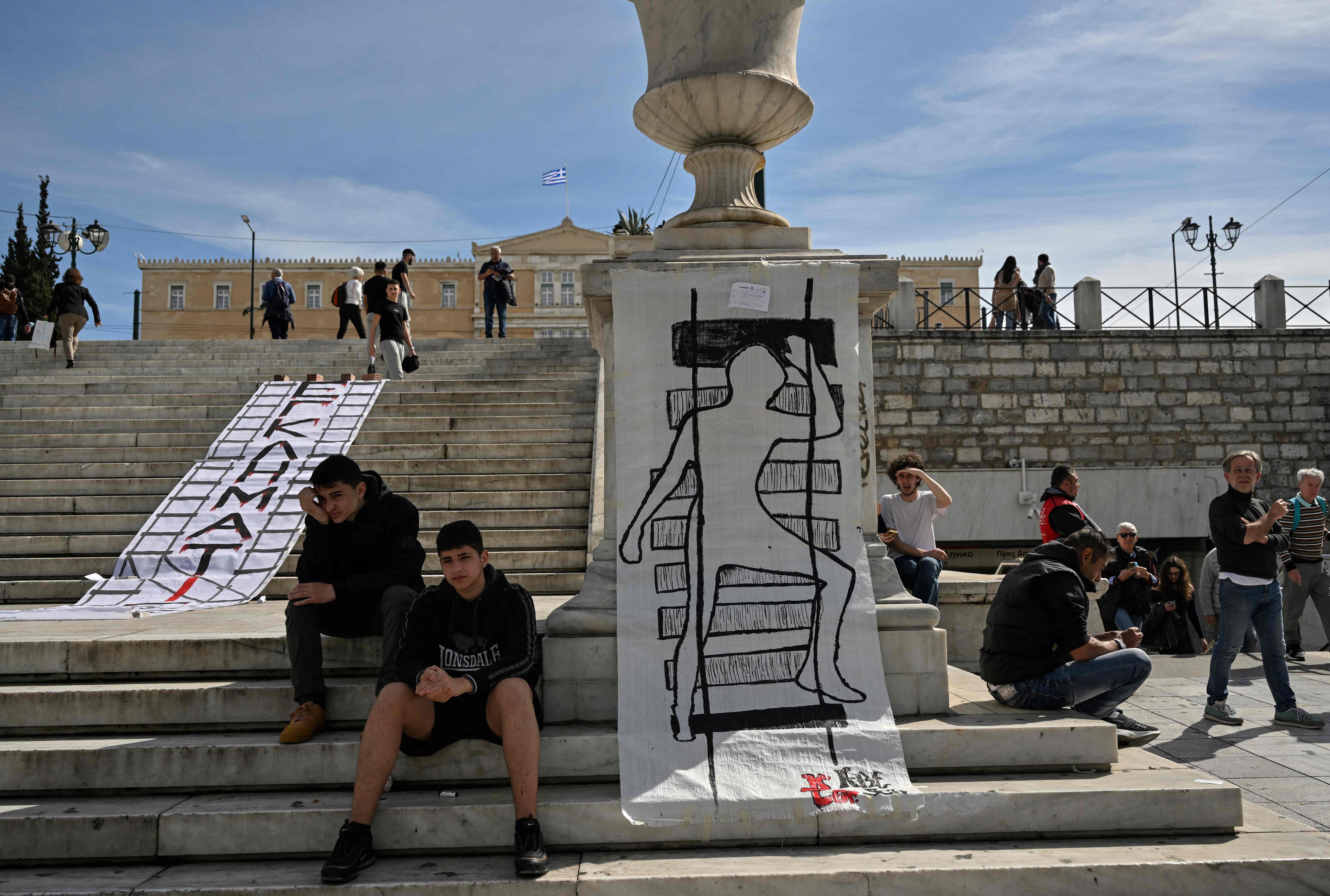 Young people pose next to a banner with the word "criminals" and another with a drawing representing a train crash victim in front of the Greek Parliament, last Friday.