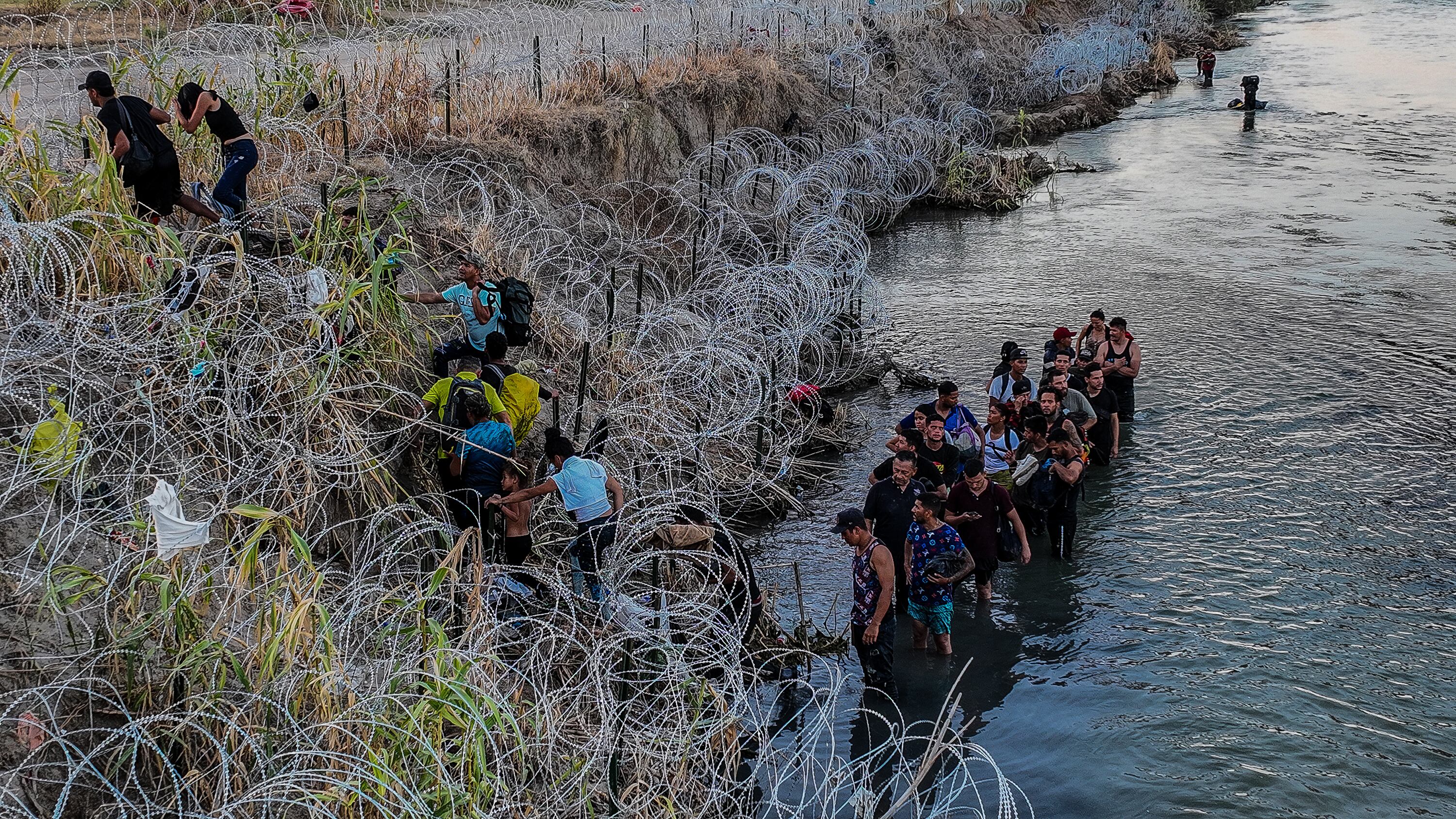 Migrants cross the barbed wire to reach Eagle Pass, Texas, in September 2023.