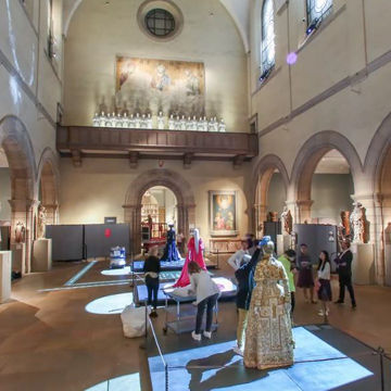 A group of people work together to install a fashion exhibition in a gallery