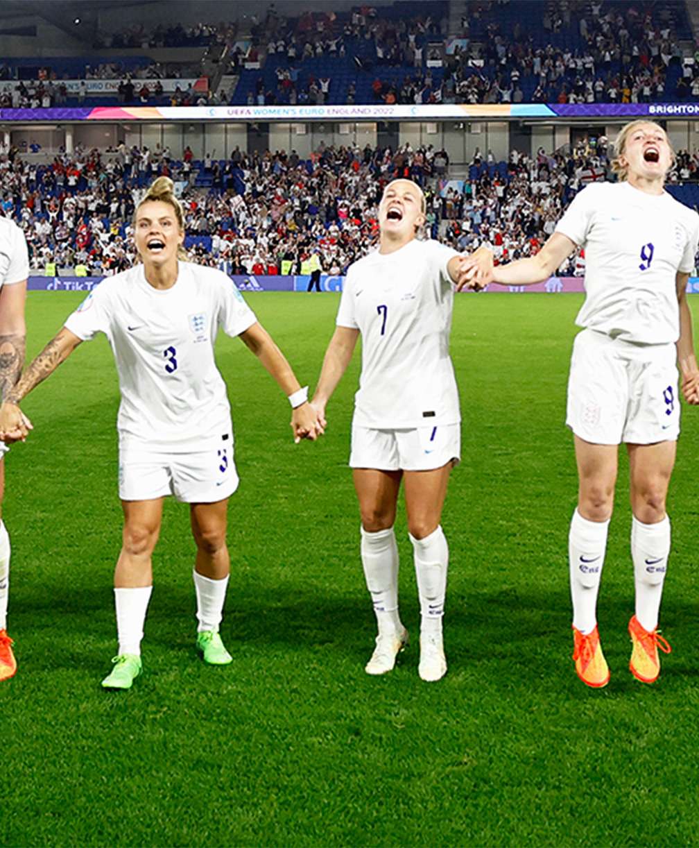 England Womens team stand in a line holding hands, cheering