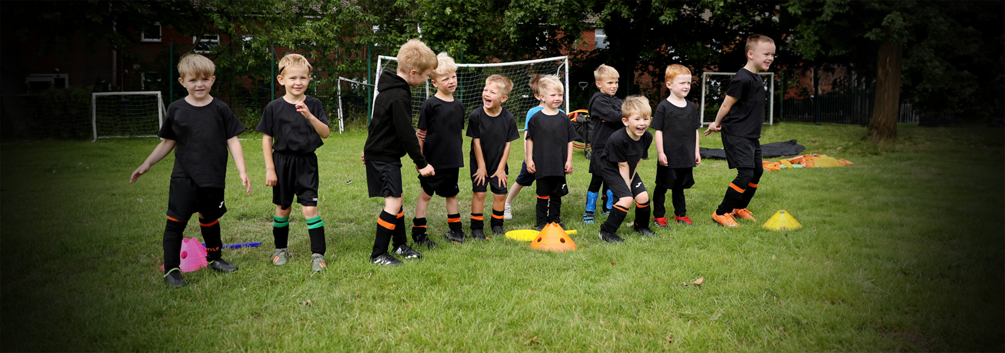 A group of young players stand in a line, they wear black kits.