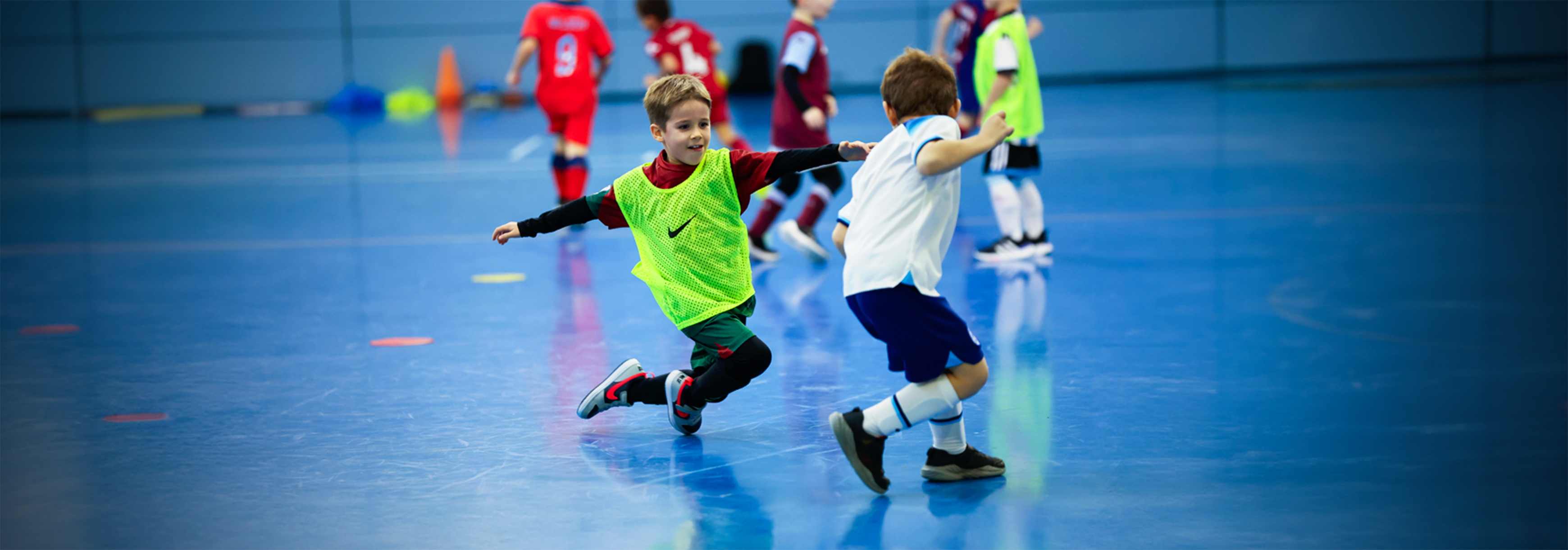 Two young players playing tag on a futsal court.