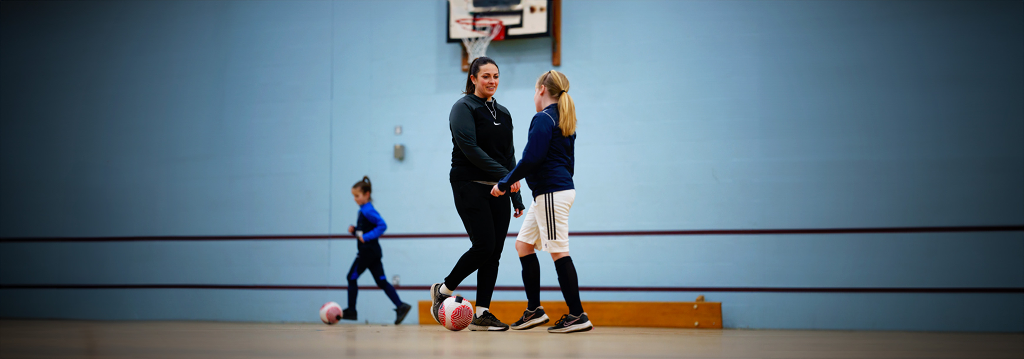 A coach talks to a player during a training session on an indoor sports hall.