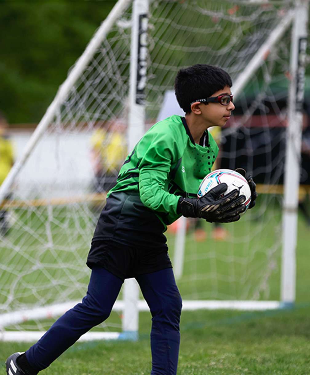 Young goalkeeper holds the ball