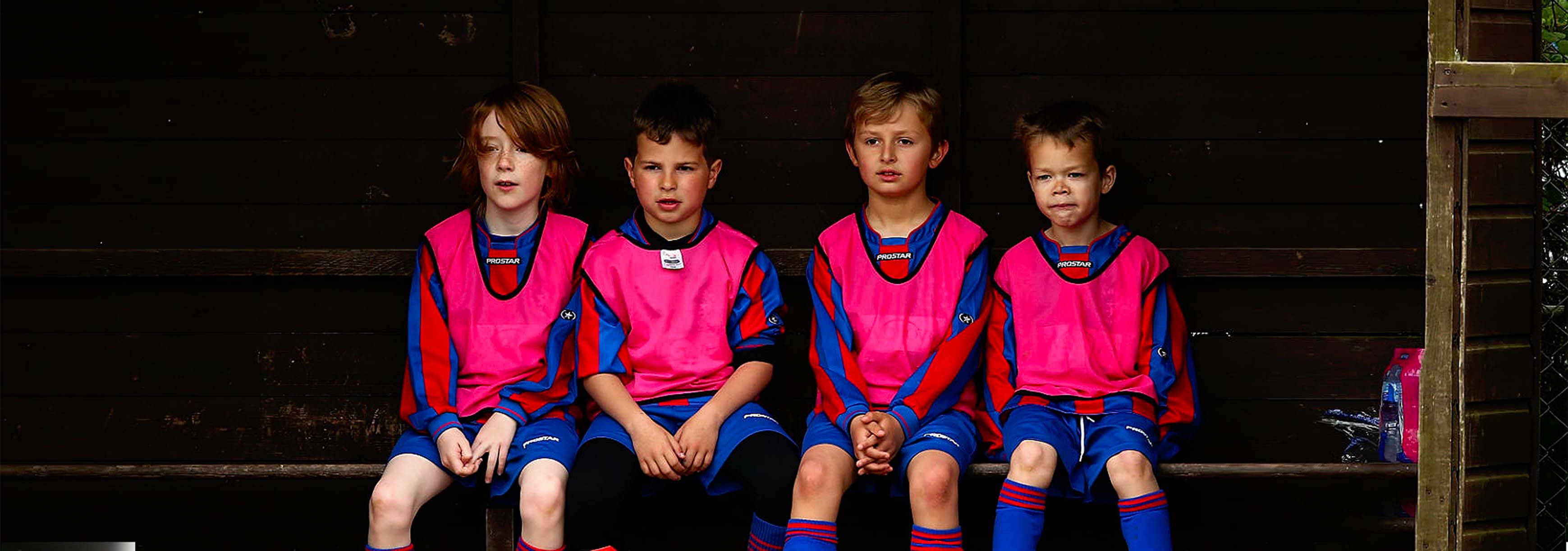 Four young players sit on a bench