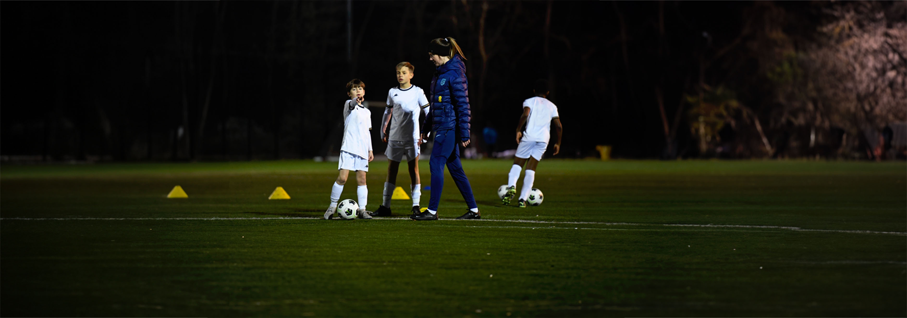 A coach talks to two players during training.