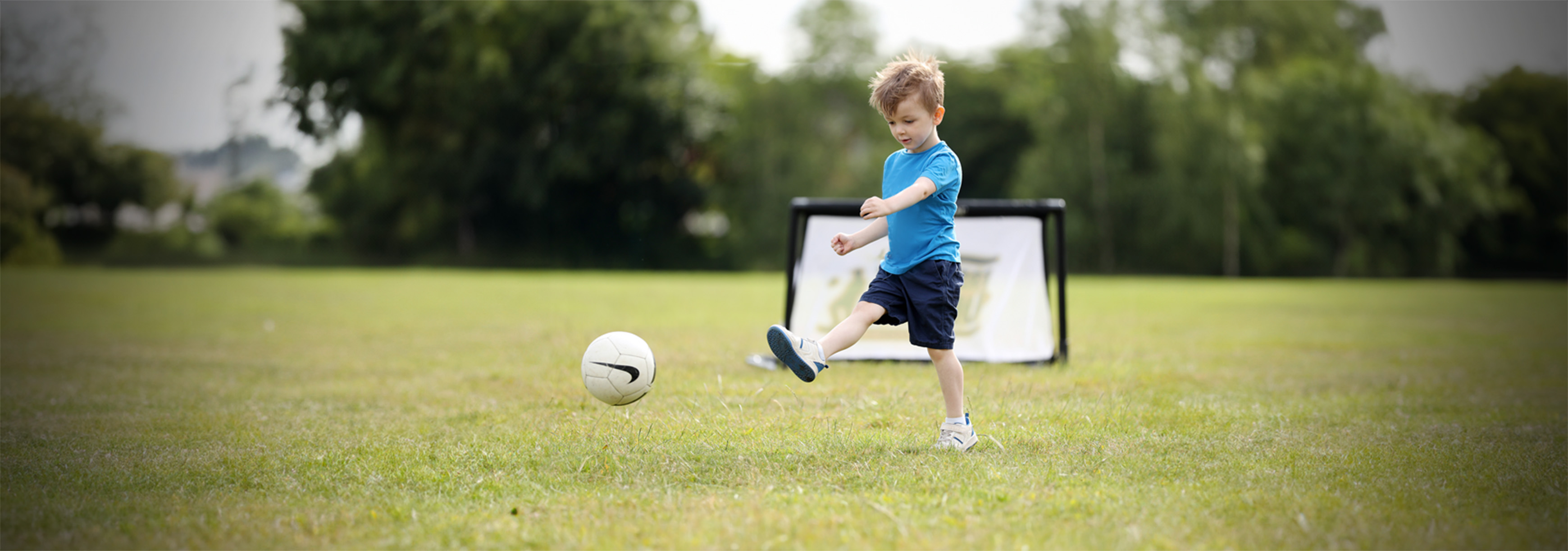 Young child kicks a ball.