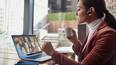 Žena pijucka šolju čaja i razgovara sa svojim saradnicima putem servisa Microsoft Teams.