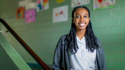 Smiling schoolgirl looking at the camera standing on a staircase.