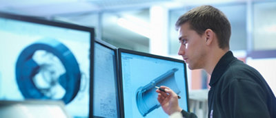 Man analyzing a 3d model on computer screens in a technical or engineering office environment.