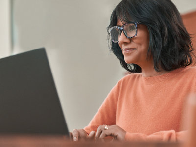 Uma mulher com óculos trabalhando com laptop