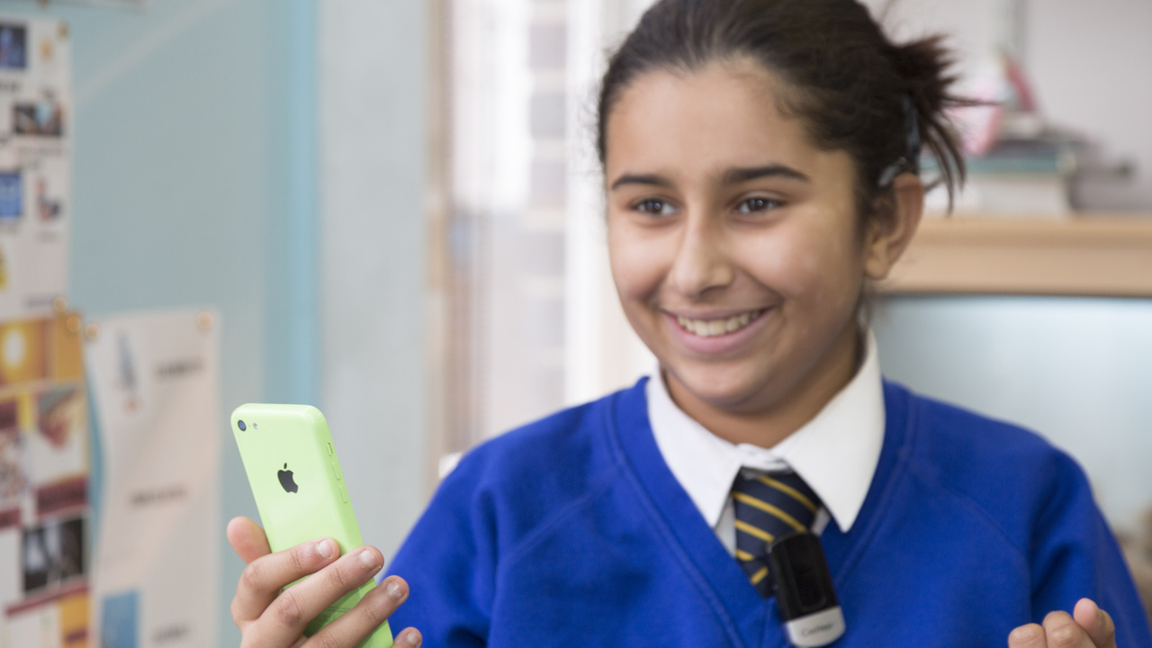 School pupil with a mobile phone in their hand