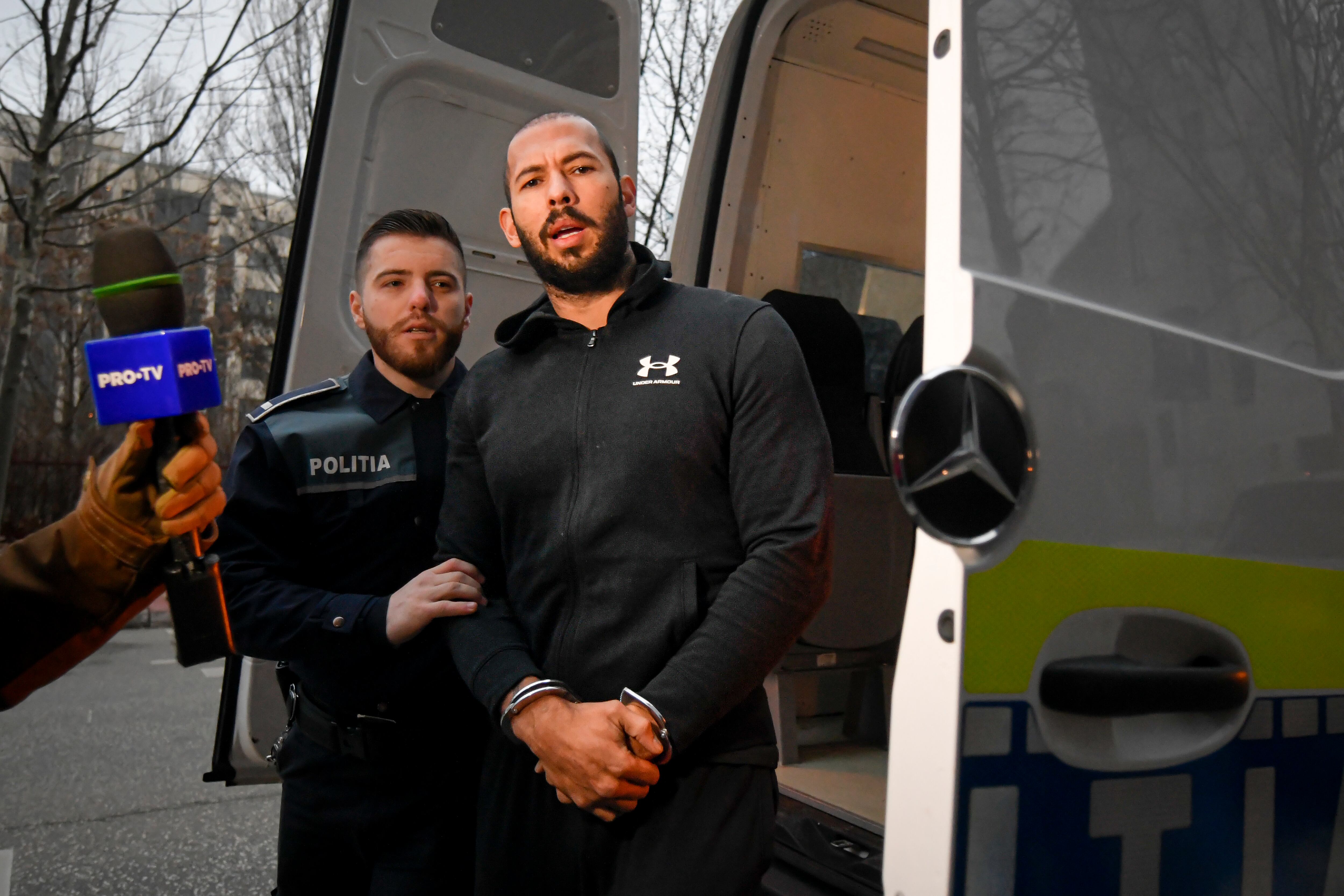 Police officers escort Andrew Tate outside the Directorate for Investigating Organized Crime and Terrorism (DIICOT) where prosecutors examine electronic equipment confiscated during the investigation in their case.